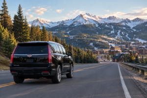 Black SUV driving toward a Colorado ski resort on a snowy mountain highway